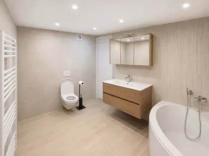 Salle de bain realisee par TL Chauffage : meuble en chene, WC suspendu et baignoire d'angle.